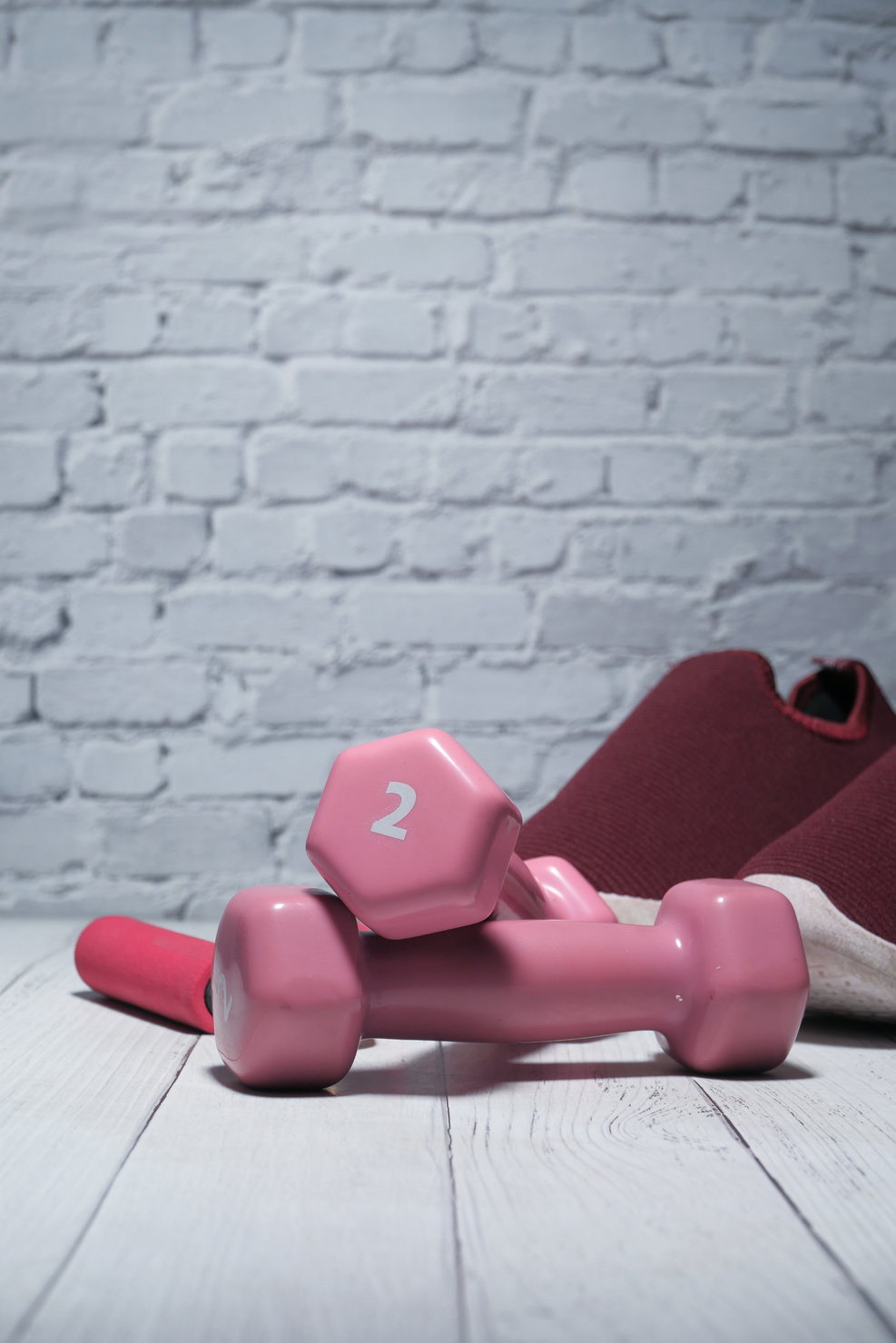 Dumbbells, Shoe and Exercise Mat on Floor against Brick Wall